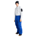 Front full body view of a man wearing the Burton AK Swash Gore-Tex 2L Snowboard Pants in Jake Blue with a white fleece top and black beanie