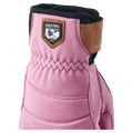 Close-up of a Cerise leather Hestra glove with a brown logo patch, elasticized wrist, and brown leather strap.