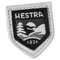 Shield-shaped Hestra logo patch with white leather trim and black embroidered mountain scene and the year 1936.