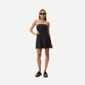 Back view of a woman wearing a white Afends Lilo strapless mini dress with a flared skirt.