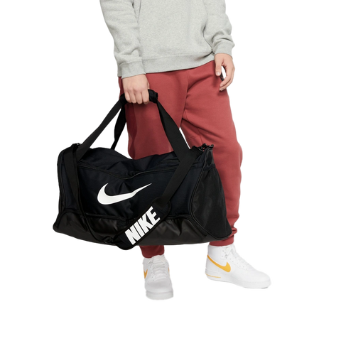 Cropped lifestyle image of Nike Brasilia Duffel in Black with brand logo in contrast White