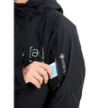 Black Burton AK Lz Gore-Tex jacket with a zippered sleeve pocket and a hand inserting a blue lift pass.