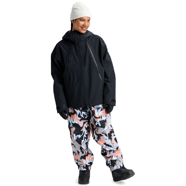 Black Burton Futuretrust 3L Snowboard Jacket with hood and oversized fit, worn with a white beanie and patterned pants.