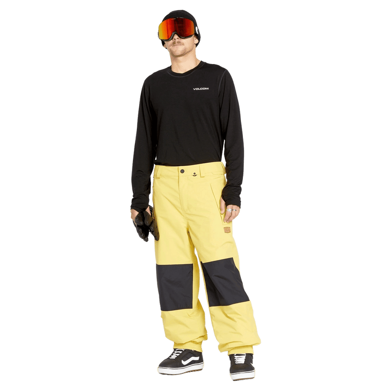 Yellow Volcom Longo Gore-Tex Snowboard Pants with black knee patches and elastic cuffs worn by a model.