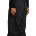 Black Volcom Kleveland snowboard pants with a hand opening a zippered outer thigh vent.