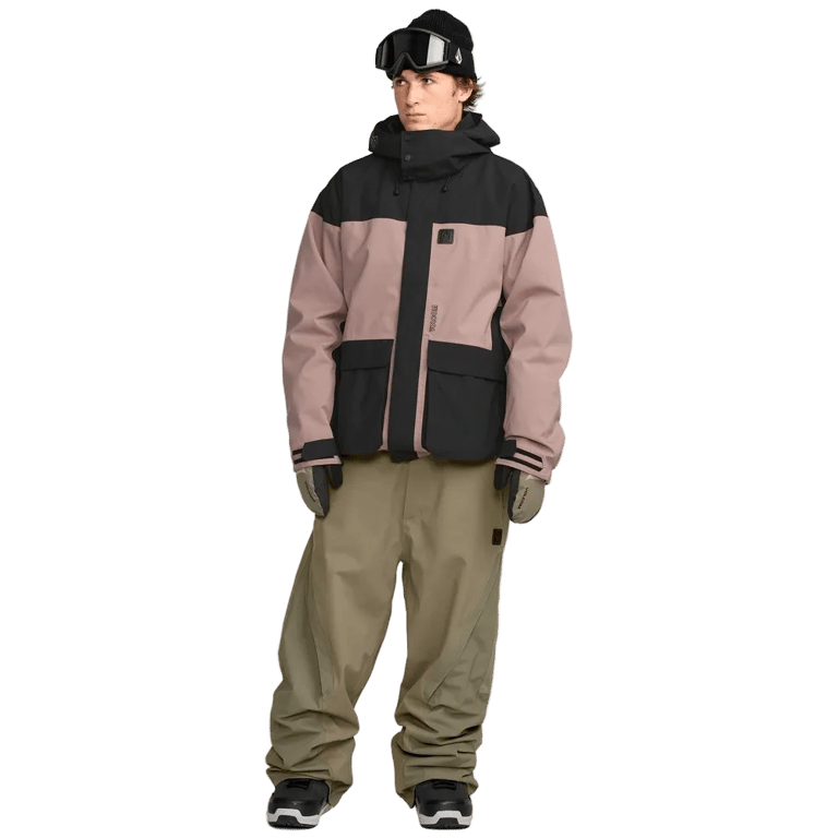 Front view of baggy olive green Volcom Kleveland Snowboard Pants on a model wearing a mauve and black jacket.