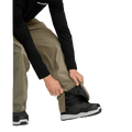 Person adjusting the zippered ankle cuff of olive Volcom Kleveland snowboard pants over a black snowboard boot.