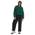 View of a woman wearing The North Face Extreme Pile 2 Pullover for Women in Hunter Green featuring a half front zip, zip chest pocket, side pockets and adjustable hem, with a small side embroidered logo on the left chest.