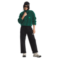 View of a woman wearing The North Face Extreme Pile 2 Pullover for Women in Hunter Green featuring a half front zip, zip chest pocket, side pockets and adjustable hem, with a small side embroidered logo on the left chest.