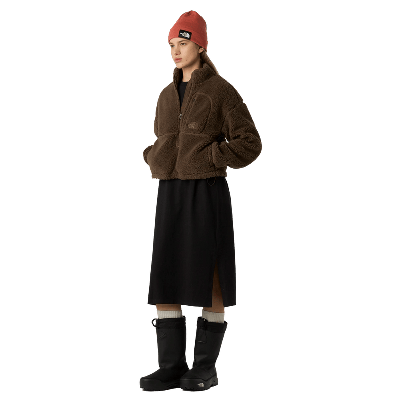 View of a woman wearing The North Face Extreme Pile 2 Pullover for Women in Smokey Brown featuring a half front zip, zip chest pocket, side pockets and adjustable hem, with a small side embroidered logo on the left chest.