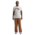 Front view of the Nike Club Pants in Ale Brown colourway, unisex model
