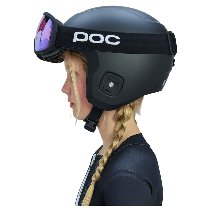 Side view of a child wearing a matte black POC Skull Dura Jr helmet with matching goggles and purple lenses.