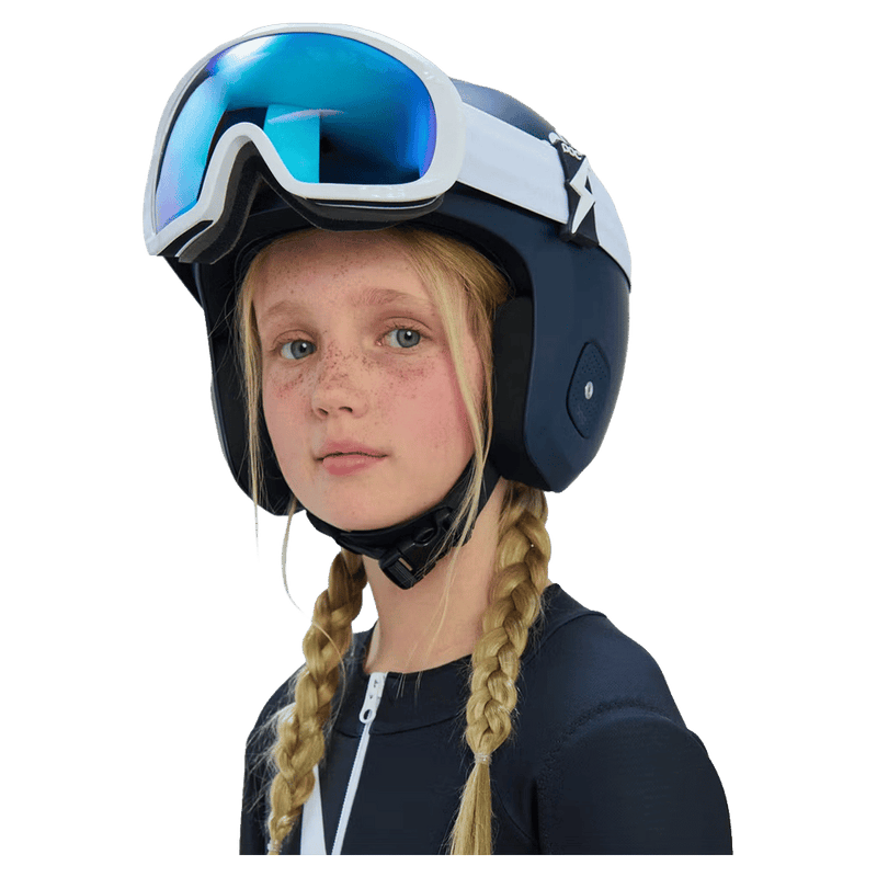 Young girl wearing a navy blue Poc Skull Dura Jr kids' ski helmet and white goggles with blue lenses.