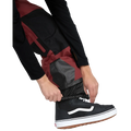 Detail, on-body image of the Rain Gore-Tex Bib Snowboard Pants from Volcom in Burnt Red. Features elasticated storm cuffs.
