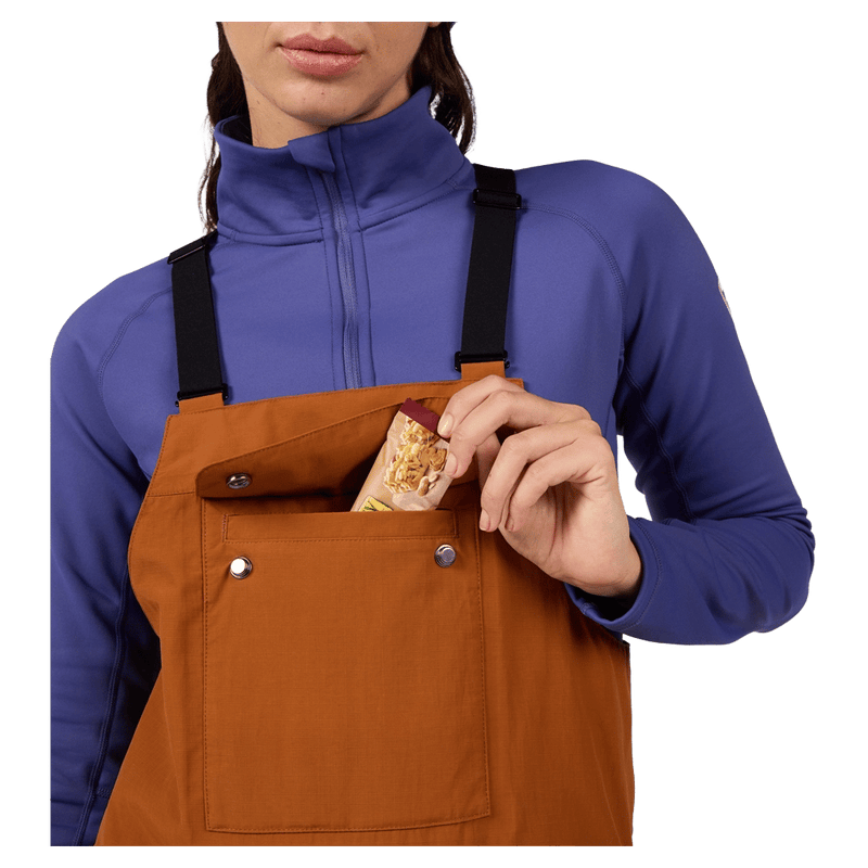Chest pocket view of the Rossignol Outerlimits Insulated Bib in DEEP CARAMEL colourway, women model