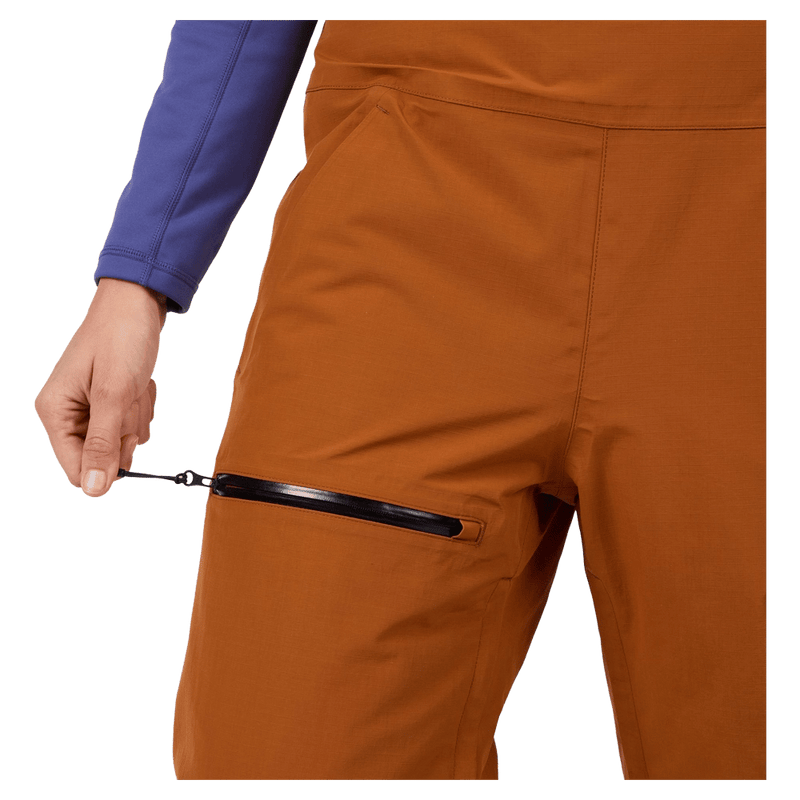 Leg pocket view of the Rossignol Outerlimits Insulated Bib in DEEP CARAMEL colourway, women model