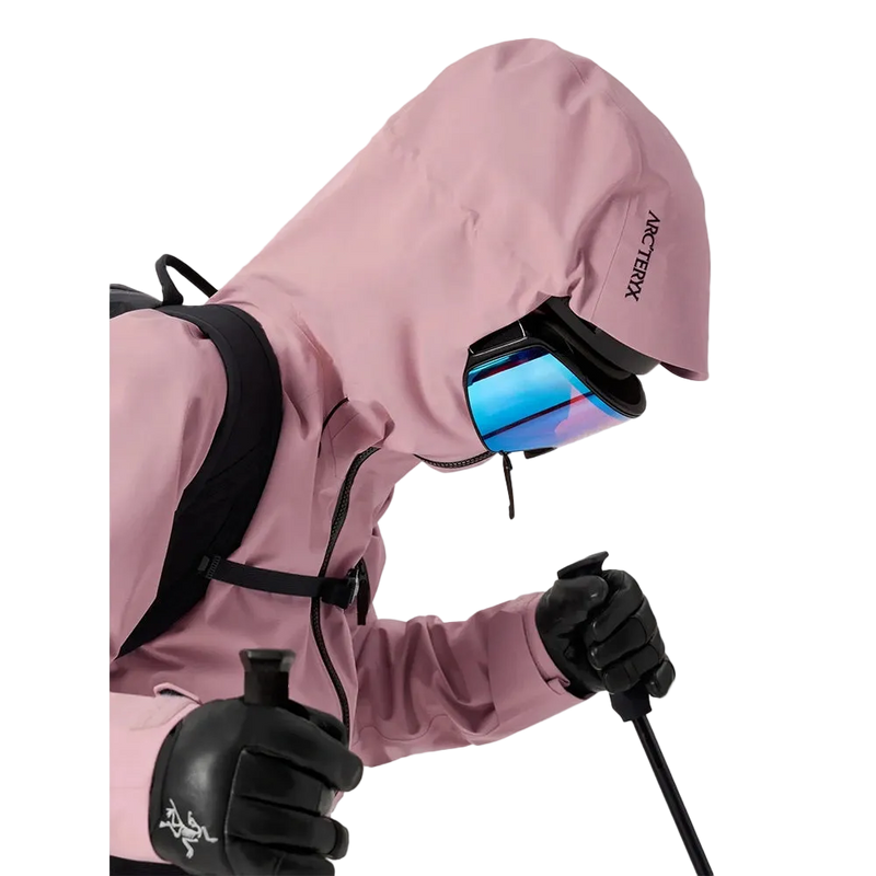 Detail view of a woman wearing the Sentinel Ski Jacket in Bliss Black featuring a helment compatible Storm Hood.