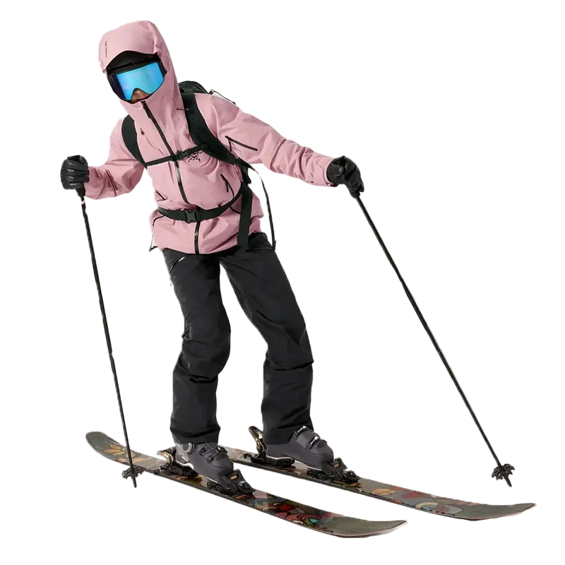 View of a woman wearing Sentinel Ski Jacket in Bliss Black with full ski gear and equipment and a backpack.