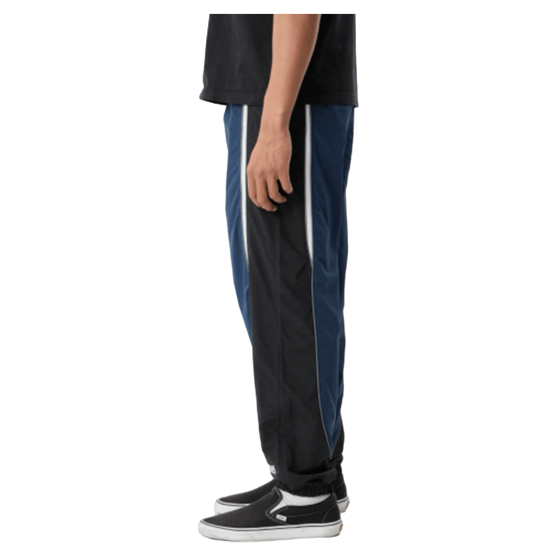 Side view of Afends Sporting Recycled Paneled Track Pants in colour Navy.
