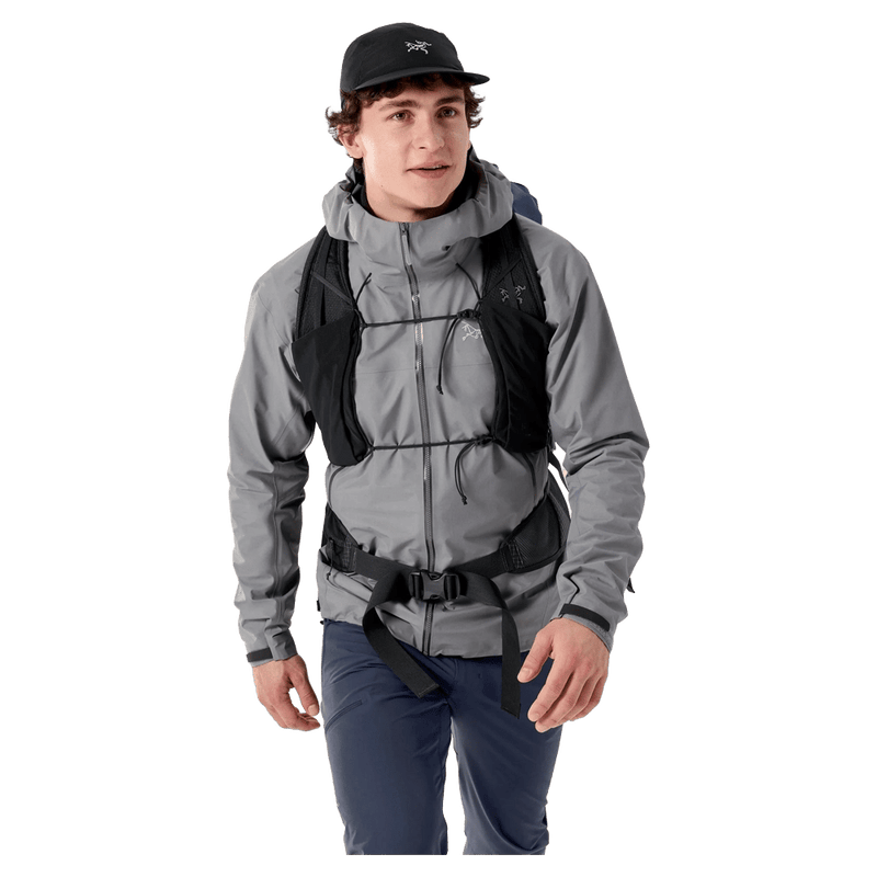 Front view of a man wearing a black Arcteryx Aerios 35 Backpack with a vest-style harness and adjustable chest straps.