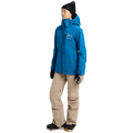 Bright blue Burton AK Upshift Gore-Tex 2L Snowboard Jacket with hood, worn with tan pants and black beanie.