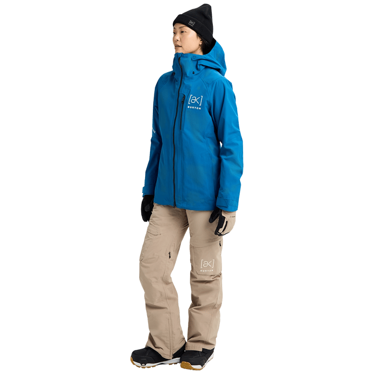 Bright blue Burton AK Upshift Gore-Tex 2L Snowboard Jacket with hood, worn with tan pants and black beanie.