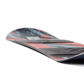 Low-angle view of a Burton Grom Camber kids' snowboard with red and blue abstract graphics and black binding plates.