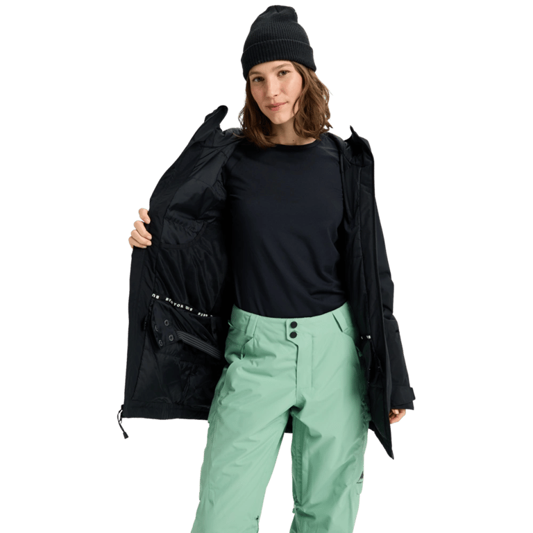 Woman wearing an open black Burton Reserve Insulated Snowboard Jacket showing the interior lining and powder skirt.