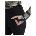 Close-up of black women's snowboard pants with a hand in a zippered side pocket and belt loops.