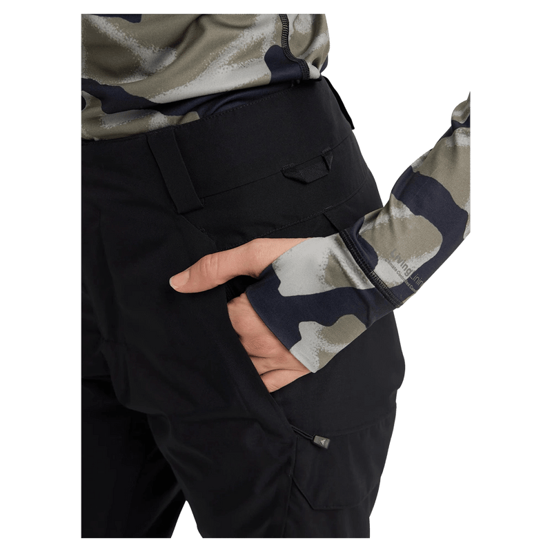 Close-up of black women's snowboard pants with a hand in a zippered side pocket and belt loops.