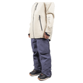 Endeavor 3L Shelter Bib Snowboard Pants in slate blue, side view showing baggy fit, worn with a cream jacket.