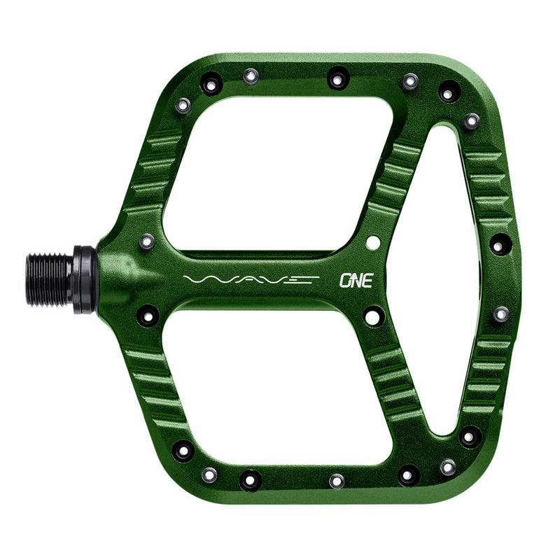 Green One Up Components Wave flat mountain bike pedal with a wavy platform design and silver traction pins.