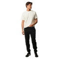 Man wearing black Rip Curl Anti Series Departed Trackpants with a white t-shirt, featuring a tapered leg and cuffed hem.