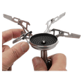 Soto Windmaster camping stove burner head with hands attaching the four-prong stainless steel pot support.