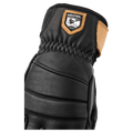 Close-up of a black Hestra Leather Fall Line glove featuring quilted leather padding, elastic wrist, and tan logo patch in colour Black