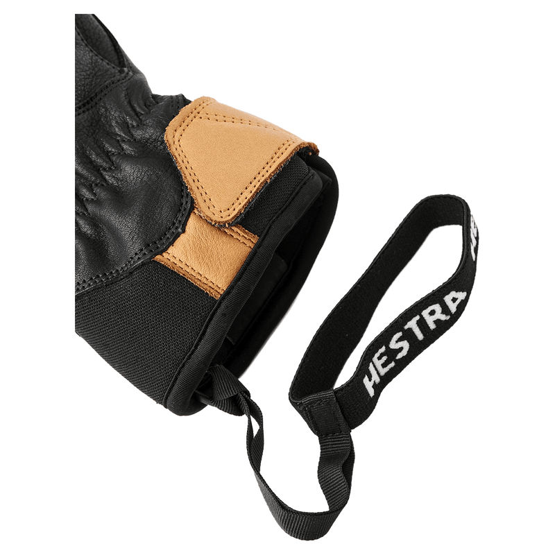 Close-up of black and tan leather Hestra glove cuff showing the Velcro closure and branded elastic wrist leash in colour Black