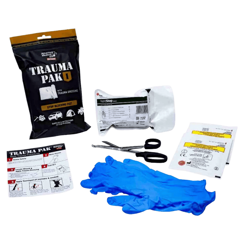 Contents laid our of the Adventure Medical Kits Trauma Pak 1 showing blue plastic gloves, scissors, instructional card, trauma dressing.