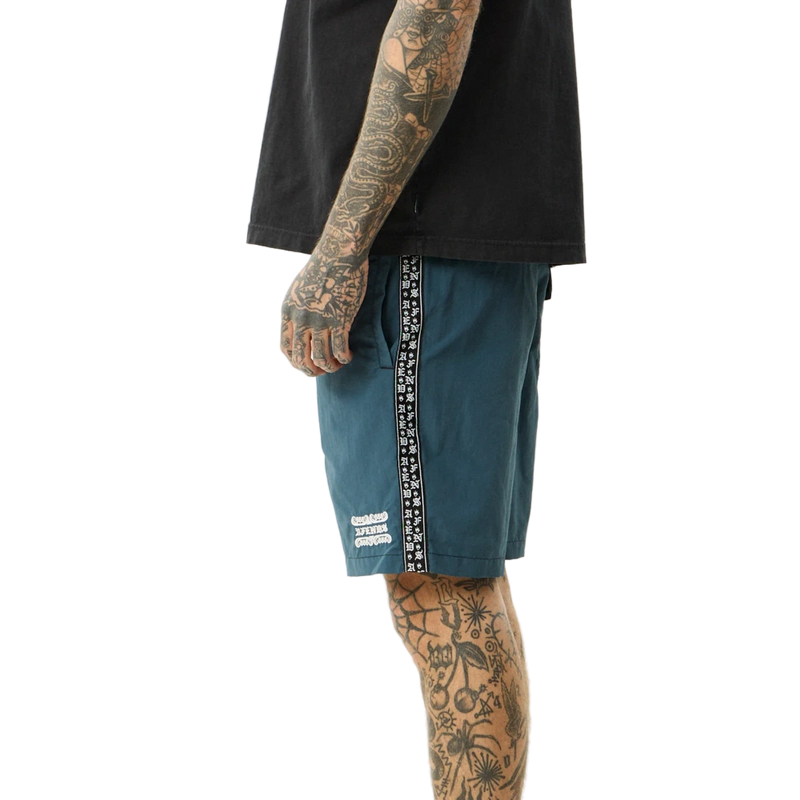 Side view of man wearing Afends Sixsixsix Recycled Baywatch Shorts in fuel colorway