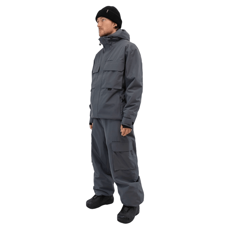 Beyond Medals Cargo 2L Snowboard Pants in slate grey with large cargo pockets, worn with a matching technical jacket.
