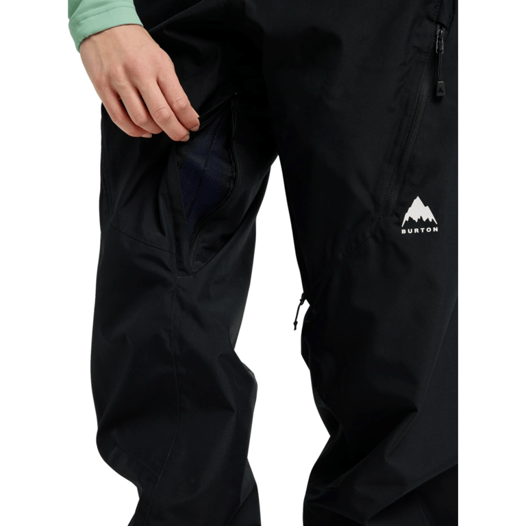 Close-up of black Burton Reserve Bib Snowboard Pants for women with a zippered thigh vent and white mountain logo.