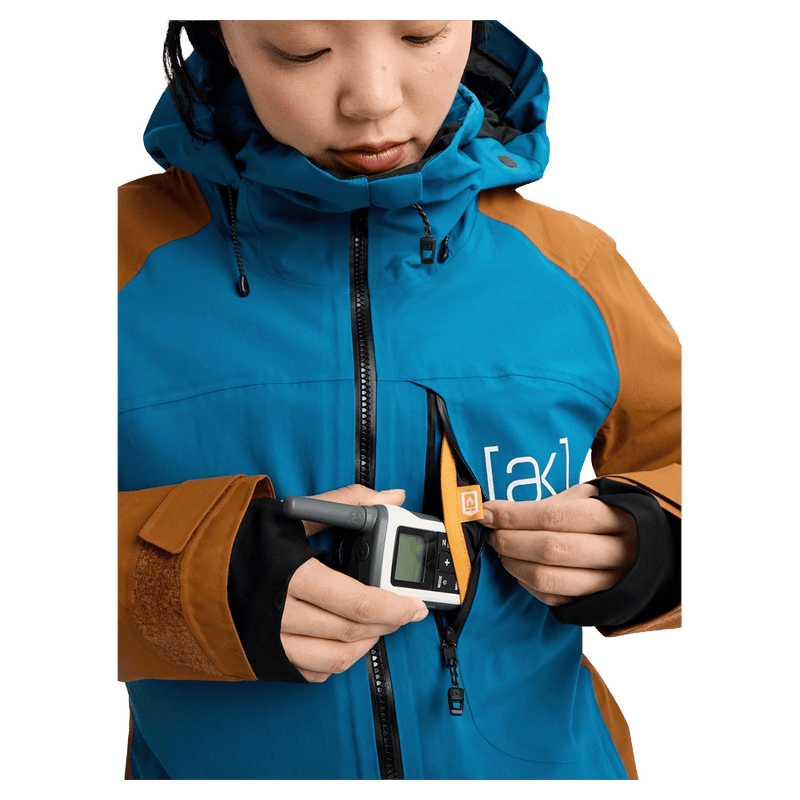 Chest pocket view of the Burton AK Embark Snowboard Jacket in Blue Teal and Chestnut colourway, women's model