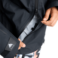 Dark Burton Futuretrust 3L Snowboard Jacket showing a large zippered pocket being opened and logo on the sleeve cuff.