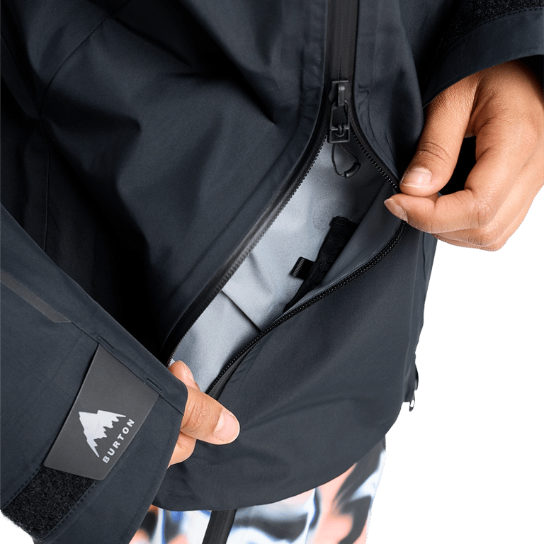 Dark Burton Futuretrust 3L Snowboard Jacket showing a large zippered pocket being opened and logo on the sleeve cuff.