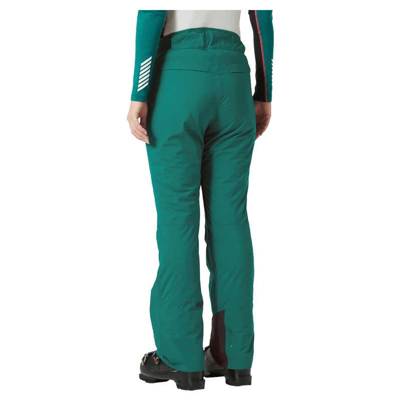 Rear view of teal Helly Hansen women's Legendary Insulated Ski Pants with reinforced cuffs and ski boots.
