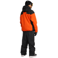 Rear view of Volcom Kleveland black snowboard pants paired with an orange and black jacket.