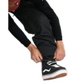 Black Volcom Longo Gore-Tex snowboard pants with elasticated ankle cuffs being adjusted over a black snowboard boot.