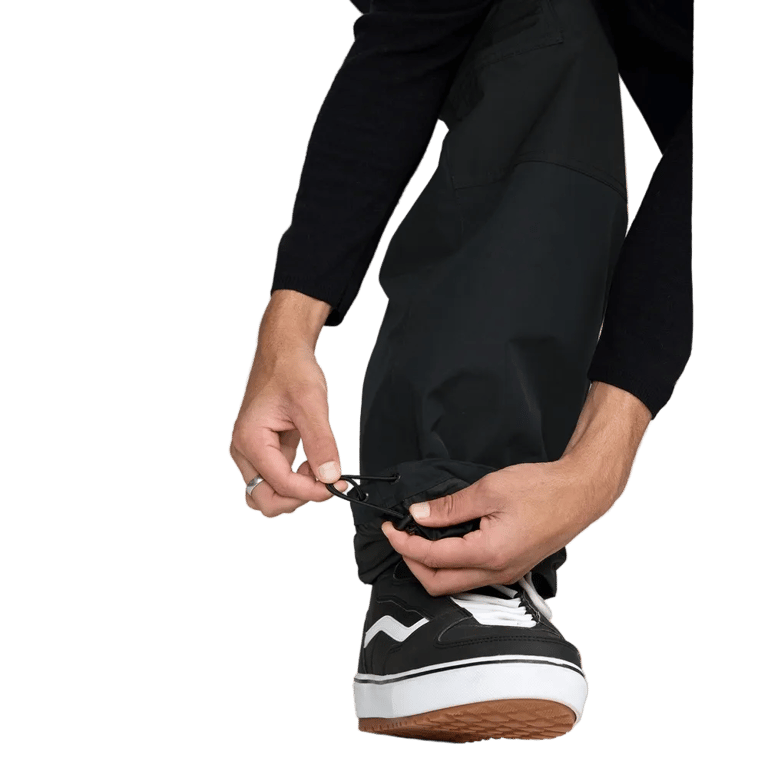 Close-up of black Volcom Longo Gore-Tex snowboard pants showing the adjustable elastic bungee cinch at the ankle.