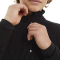Child wearing a black Elude Microfleece 1/4 Zip Top with hands adjusting the zipper on the high collar.