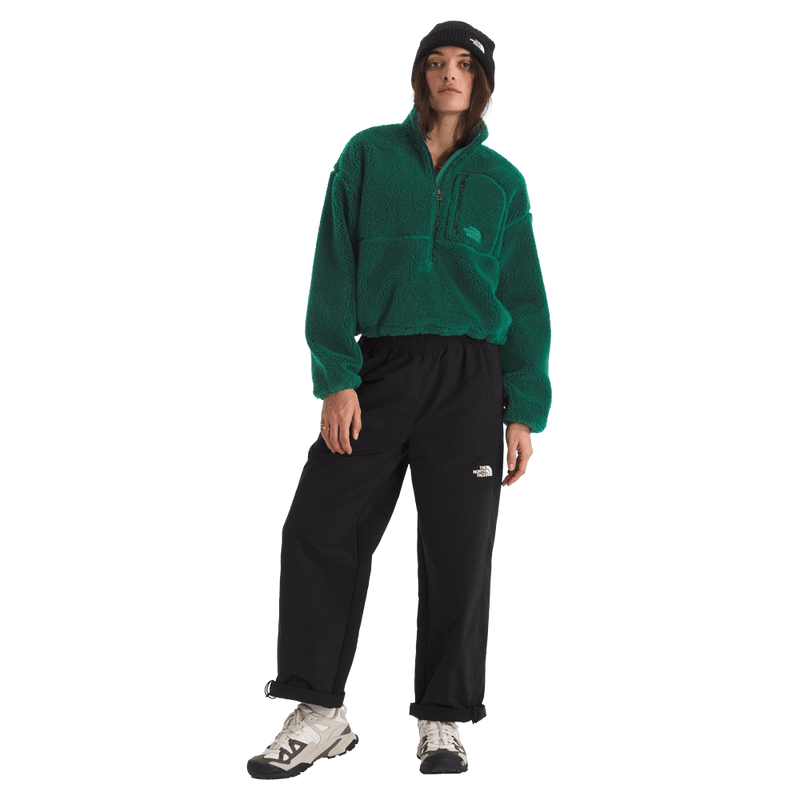 View of a woman wearing The North Face Extreme Pile 2 Pullover for Women in Hunter Green featuring a half front zip, zip chest pocket, side pockets and adjustable hem, with a small side embroidered logo on the left chest.