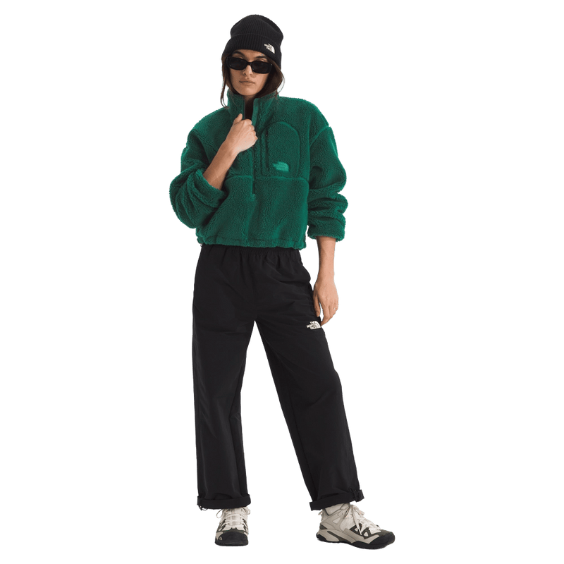 View of a woman wearing The North Face Extreme Pile 2 Pullover for Women in Hunter Green featuring a half front zip, zip chest pocket, side pockets and adjustable hem, with a small side embroidered logo on the left chest.